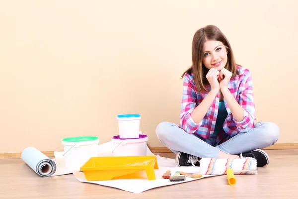 Menina bonita sentada no chão com equipamento para pintura de parede — Fotografia de Stock