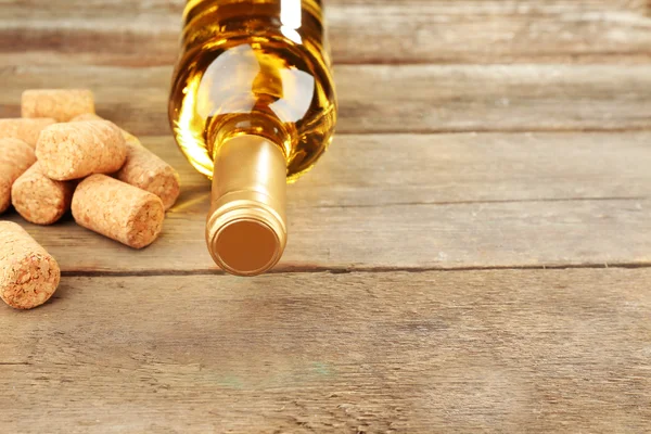 Botella de vino con corchos sobre fondo de mesa de madera —  Fotos de Stock