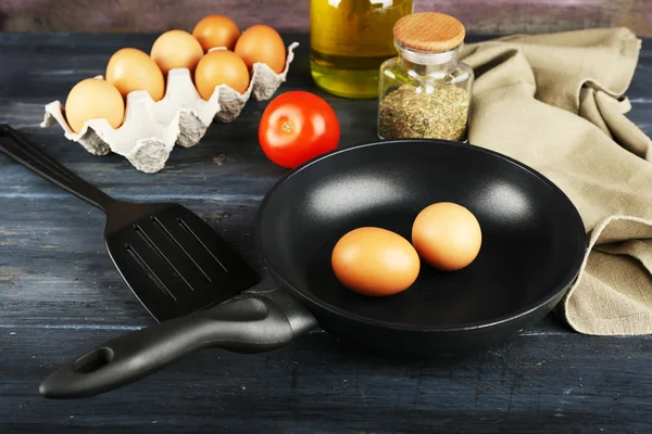Натюрморт з яйцями і сковородою на дерев'яному фоні — стокове фото