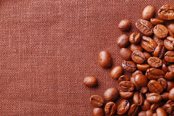 Frame of coffee beans on color sackcloth background — Stock Photo, Image