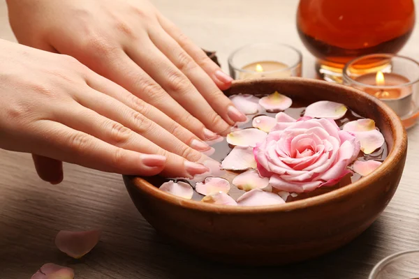 Manos femeninas y tazón de agua de spa con flores, primer plano — Foto de Stock