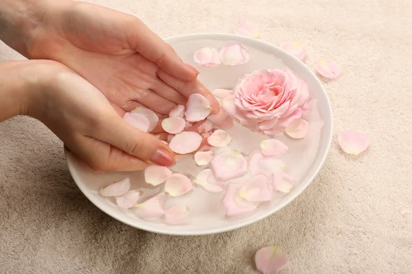 Mãos femininas com tigela de água de spa de aroma na mesa, close-up — Fotografia de Stock