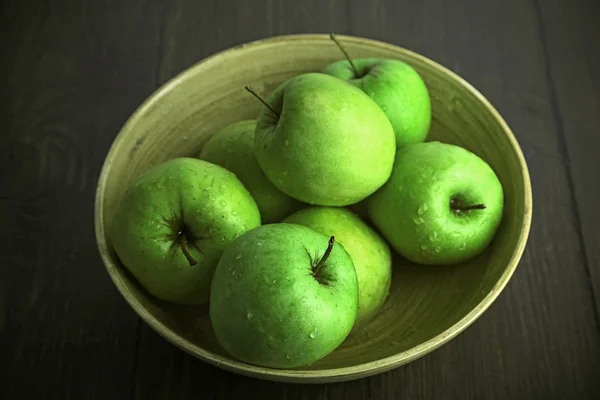 Zelená jablka v misce na dřevěný stůl, detail — Stock fotografie