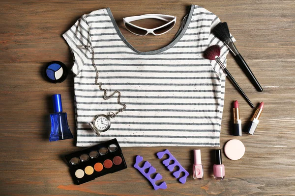 Striped T-shirt and various cosmetics on wooden background — Stock Photo, Image