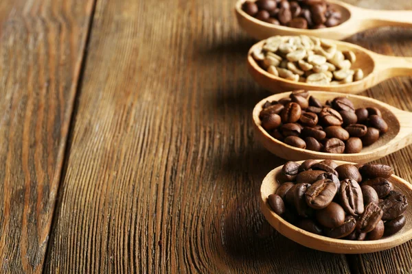 Coffee beans in spoons on wooden background — Stock Photo, Image