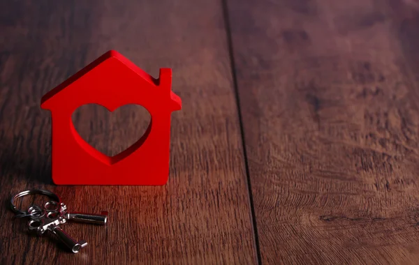 Toy house med nyckel på trä bakgrund — Stockfoto