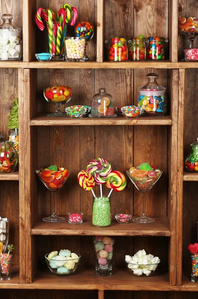 Красочные конфеты в банках на деревянных полках крупным планом — стоковое фото