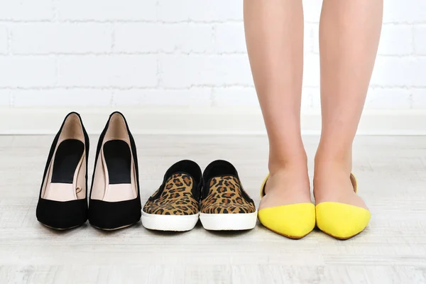 Menina escolhe sapatos no quarto no fundo cinza — Fotografia de Stock