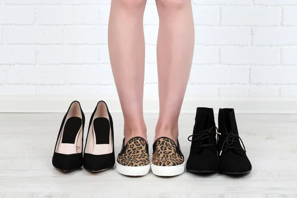 Menina escolhe sapatos no quarto no fundo cinza — Fotografia de Stock
