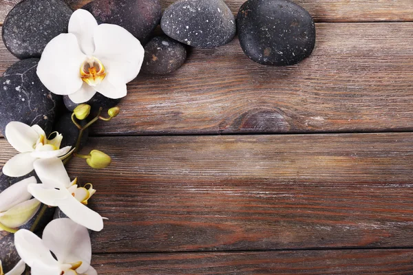 Piedras de spa y flor de orquídea sobre fondo de madera —  Fotos de Stock