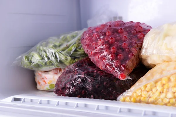 Frutas e legumes congelados em sacos no congelador de perto — Fotografia de Stock