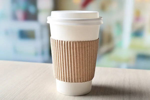 Бумажная чашка кофе на столе на ярком фоне — стоковое фото