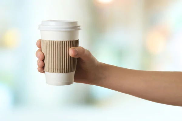 Рука держит бумажную чашку кофе на ярком фоне — стоковое фото
