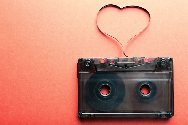 Cassette de audio con cinta magnética en forma de corazón sobre fondo rojo — Foto de Stock