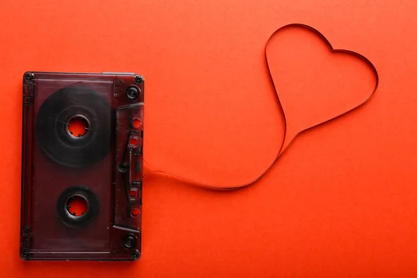 Cassete de áudio com fita magnética em forma de coração sobre fundo vermelho — Fotografia de Stock