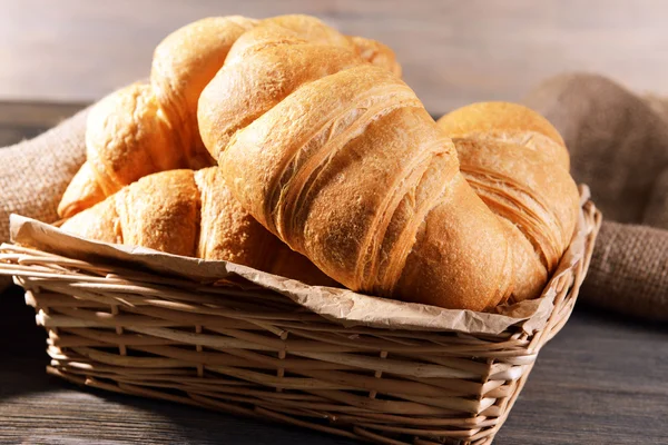 Delicious croissants in wicker basket on table close-up — Stock Photo, Image