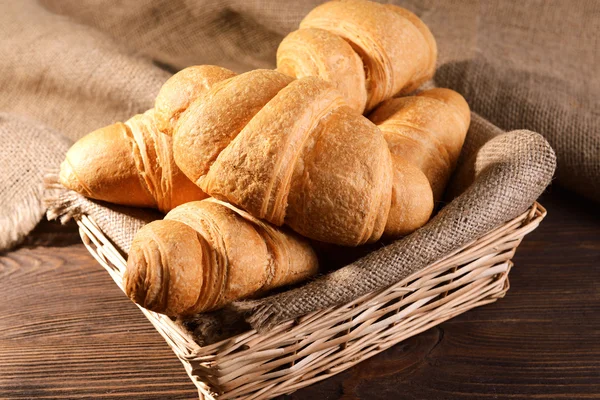 Deliciosos croissants en canasta de mimbre en primer plano de mesa —  Fotos de Stock