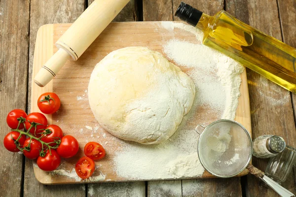 Dough on cutting board with cherry and oil on table close up — Stock Photo, Image
