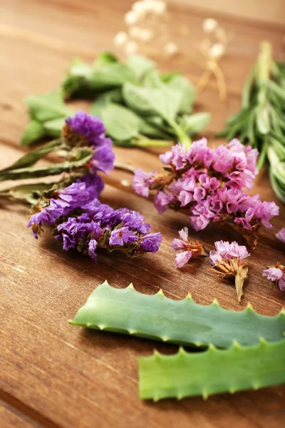 Groene kruiden en bladeren op houten tafel, close-up — Stockfoto