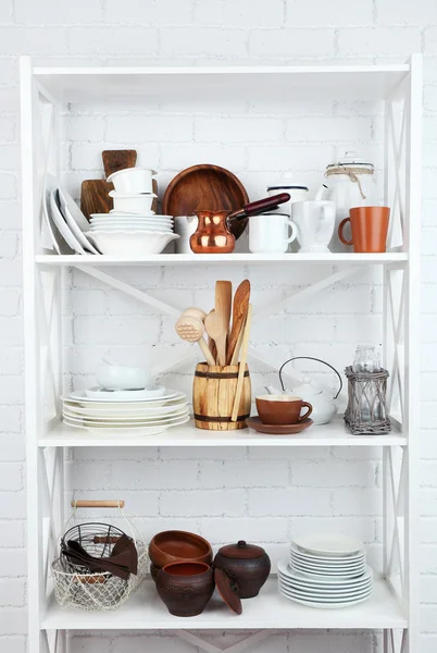 Кухонные полки с посудой на фоне белой кирпичной стены — стоковое фото