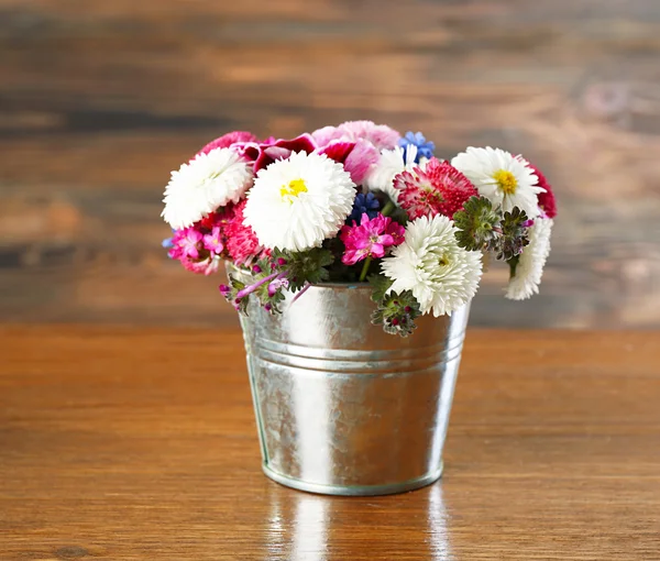 Buntes Gänseblümchen im Metalleimer auf Holzgrund — Stockfoto