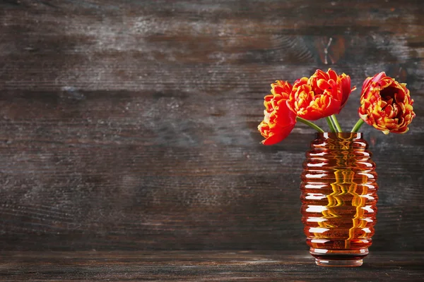 Mooi oranje tulpen in glazen vaas op houten achtergrond — Stockfoto