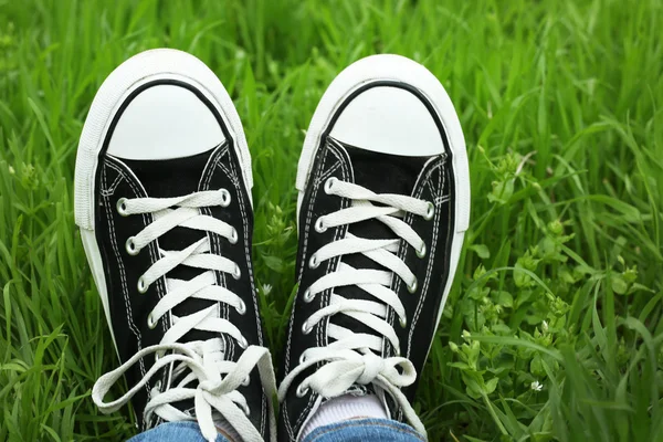 Female feet in gumshoes on green grass background — Stock Photo, Image