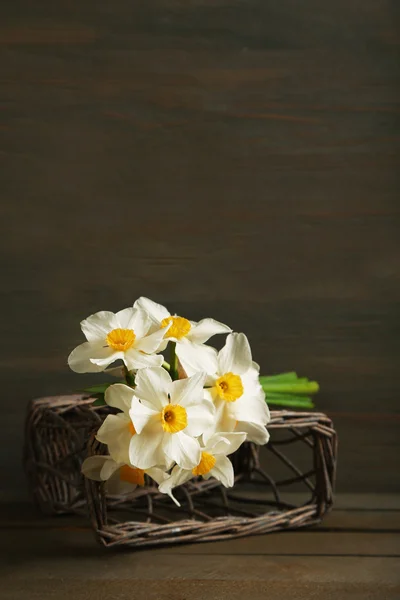 Narciso fresco com cesta de vime em fundo de madeira — Fotografia de Stock
