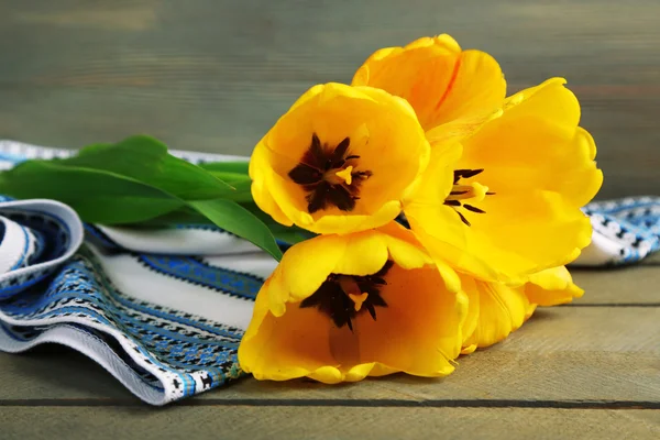 Hermosos tulipanes amarillos con servilleta sobre fondo de madera — Foto de Stock