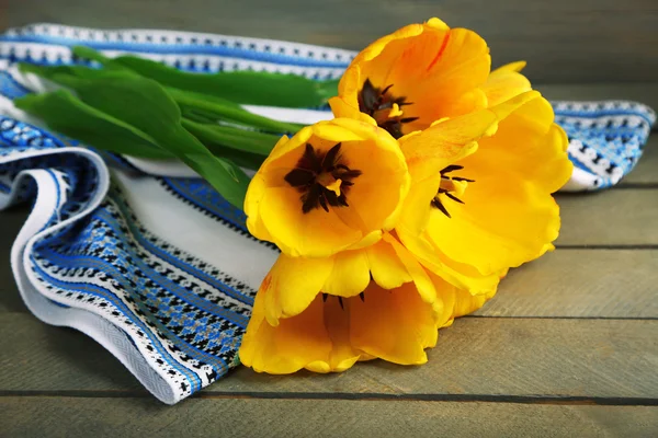 Beautiful yellow tulips with napkin on wooden background — Stock Photo, Image