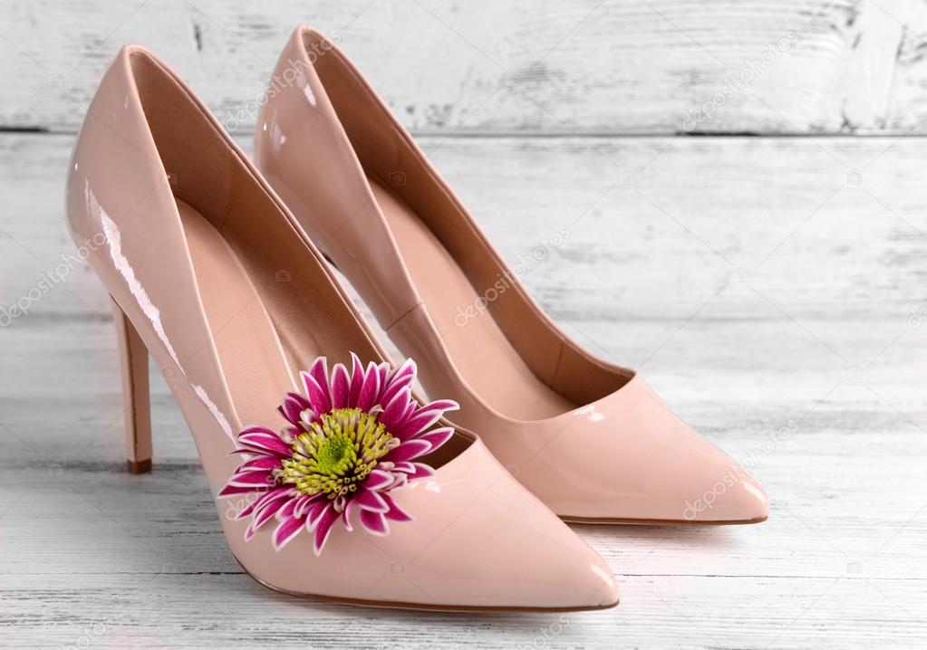 Female shoes with flower on wooden background