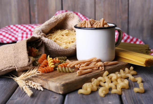 Different types of pasta in containers on wooden background — Stock Photo, Image