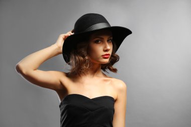 Siyah elbise ve şapka gri arka plan üzerinde güzel model portresi