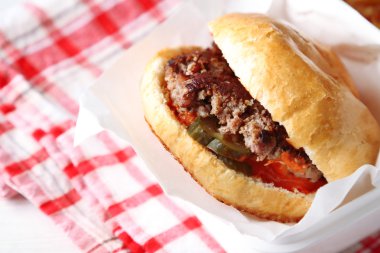 Lezzetli burger kağıt peçeteye, ahşap masa arka plan, yakın çekim. Sağlıksız yiyecek konsepti