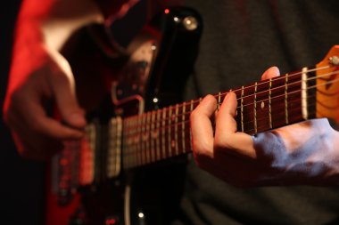 Genç adam elektro gitarla oynuyor. Yakın plan.