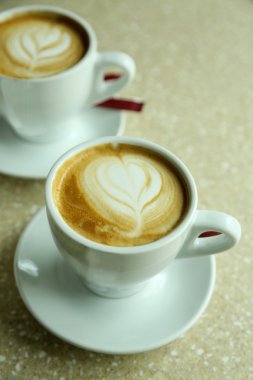 Kapuçino kafede masada köpük üzerinde kalpli bardak