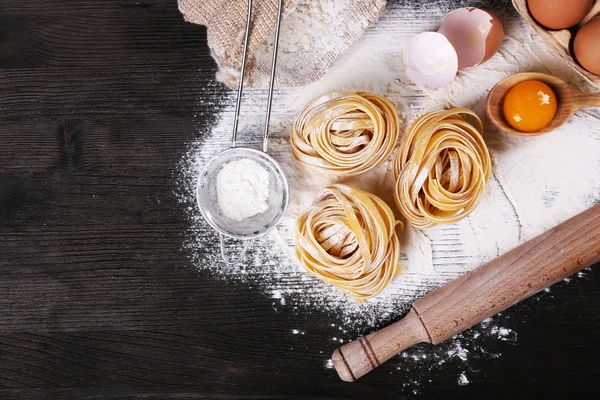 Syrové domácí těstoviny a ingredience pro těstoviny na dřevěné pozadí — Stock fotografie