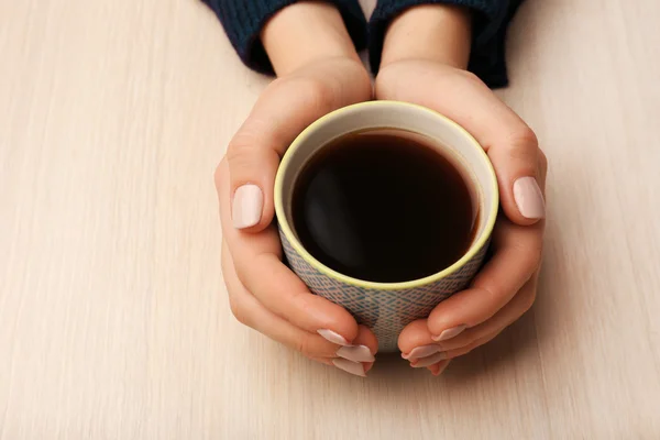 Tangan wanita memegang cangkir kopi dengan latar belakang kayu — Stok Foto