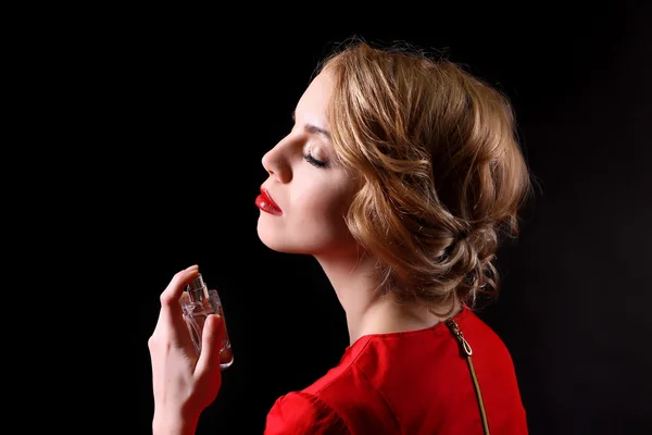 Belle jeune femme avec bouteille de parfum sur fond noir — Photo