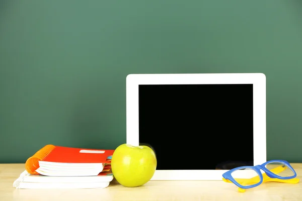 Tablet op tafel, op groene krijtbord achtergrond — Stockfoto