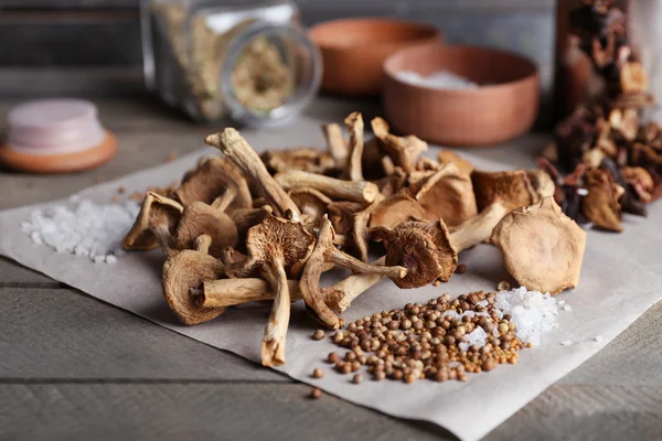 Gedroogde champignons met specerijen op papier op houten tafel, close-up — Stockfoto