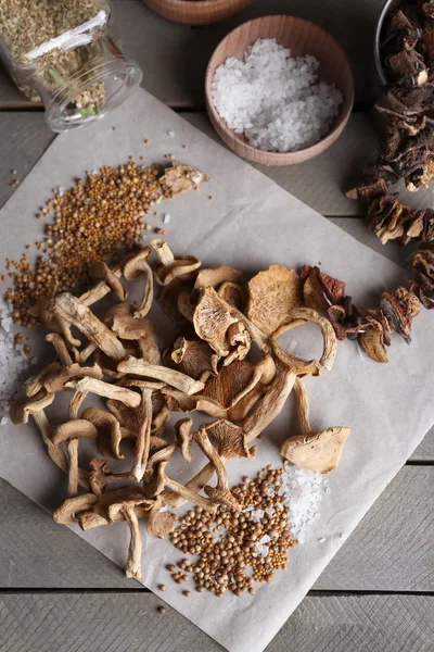 Gedroogde champignons met specerijen op papier op houten tafel, bovenaanzicht — Stockfoto