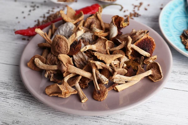 Сушеные грибы в тарелке на деревянном фоне — стоковое фото
