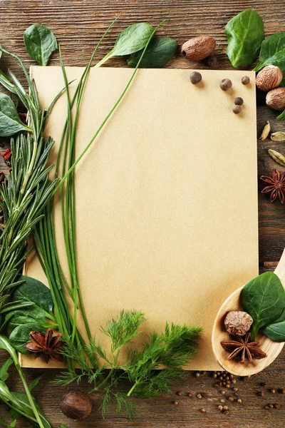 Libro de recetas abierto con hierbas frescas y especias sobre fondo de madera — Foto de Stock