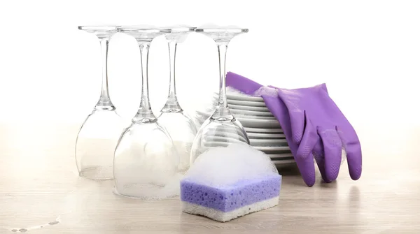 Platos en espuma con guantes y wisp sobre mesa aislados en blanco — Foto de Stock