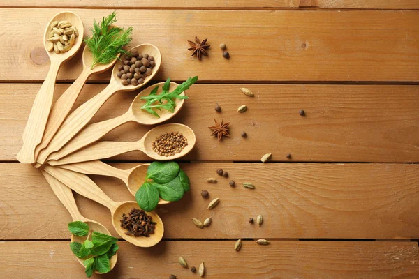 Cucchiai di legno con erbe fresche e spezie su sfondo di legno — Foto Stock