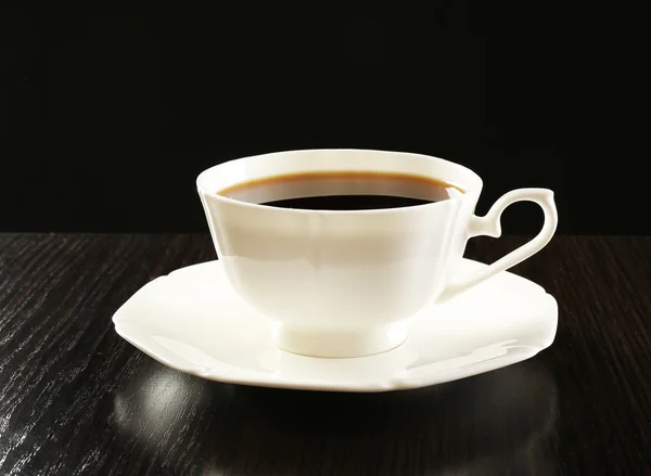 Cup of coffee on wooden table, on dark background — Stock Photo, Image