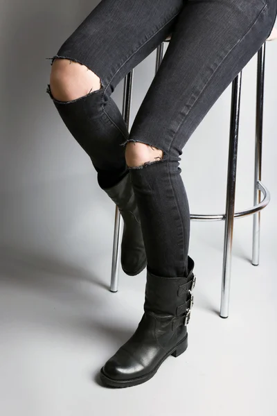 Pernas de menina em jeans rasgado no fundo cinza — Fotografia de Stock