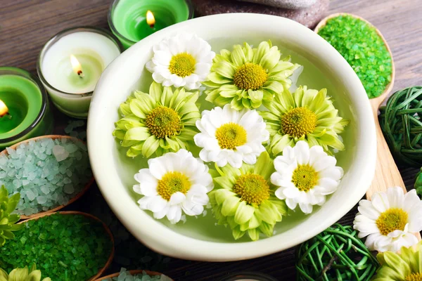 Beautiful composition with sea salt in wooden spoons and flowers on table close up — Stock Photo, Image