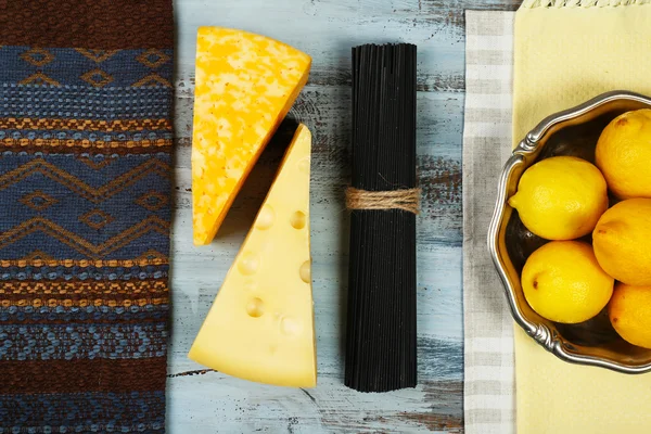 奶酪、 黑色的意大利面条和柠檬在木桌上面查看 — 图库照片